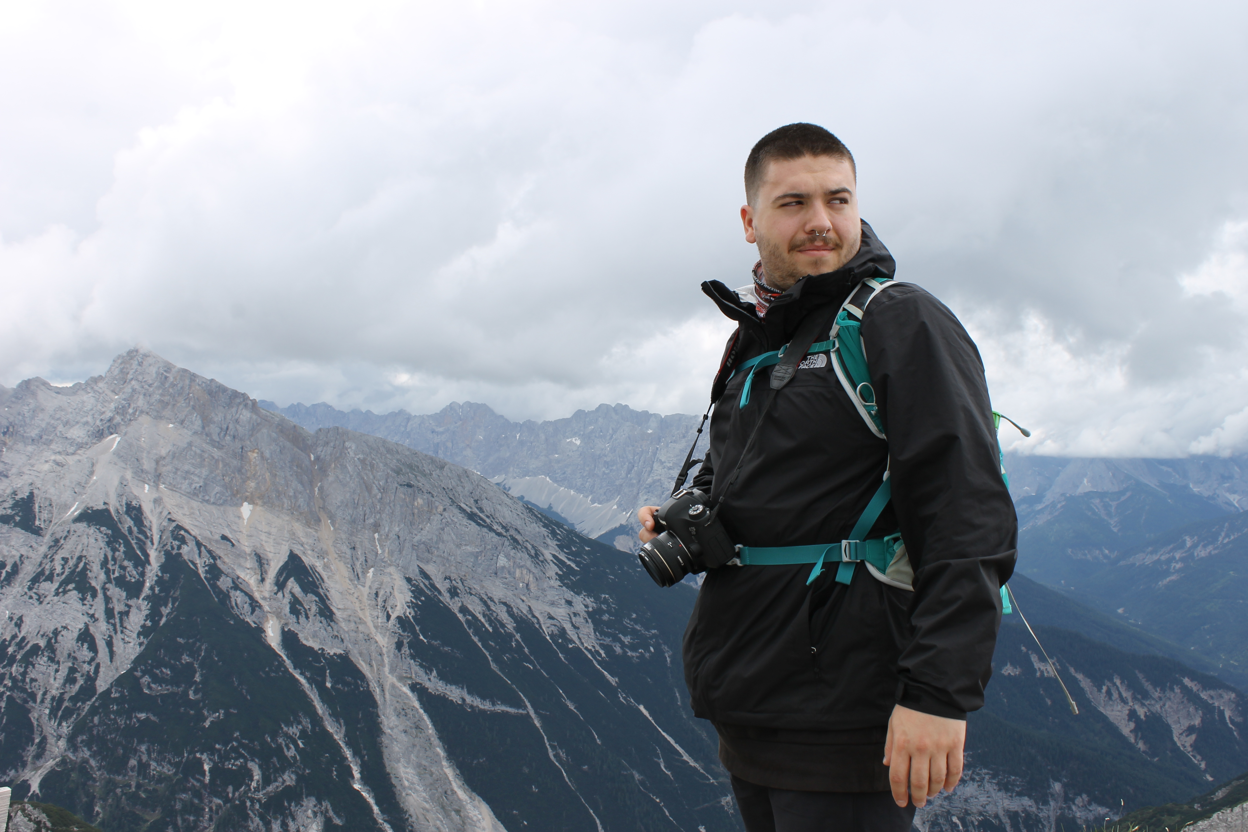 A grantee stands atop a mountain holding a camera